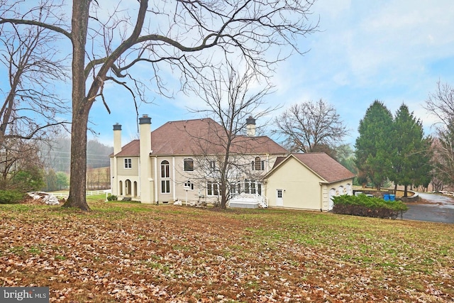 back of house featuring a lawn and a chimney