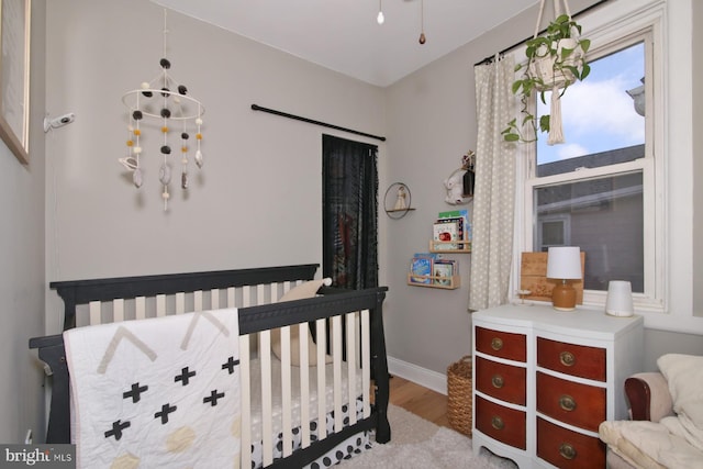 bedroom with light wood-style floors, a notable chandelier, and baseboards