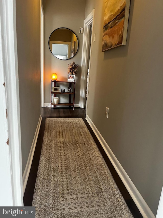 corridor with baseboards and dark wood-style flooring