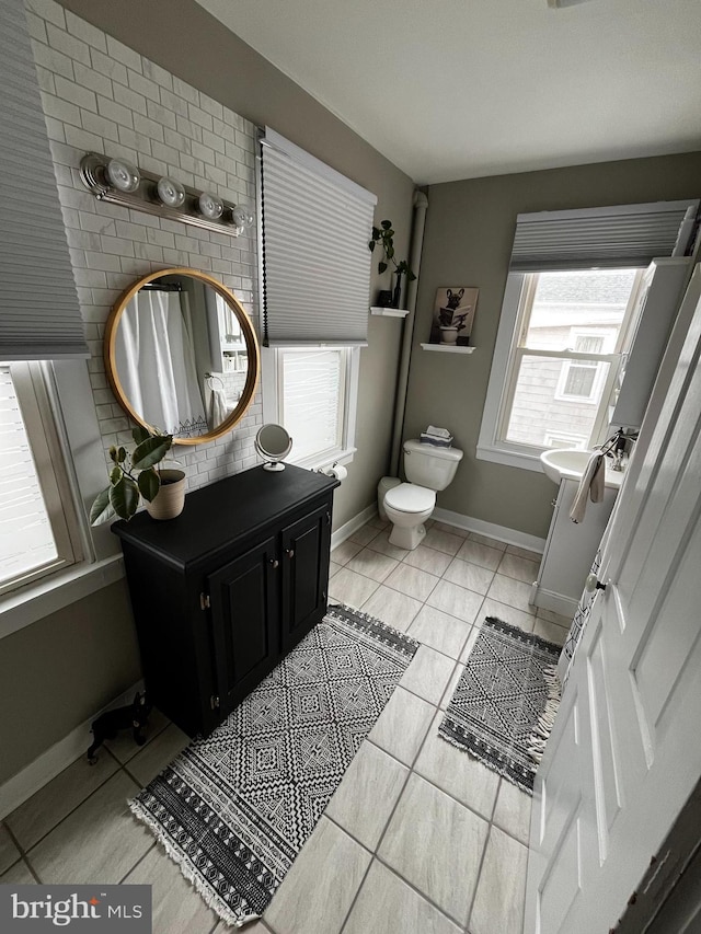 bathroom with tile patterned flooring, baseboards, and toilet