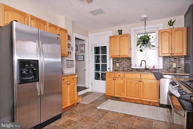 kitchen with light stone countertops, visible vents, appliances with stainless steel finishes, and tasteful backsplash