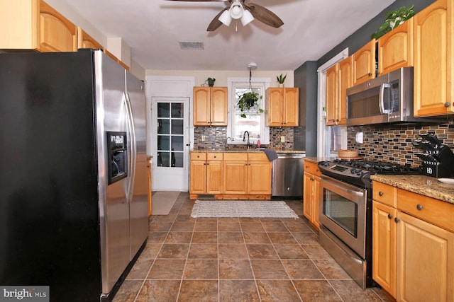 kitchen with visible vents, appliances with stainless steel finishes, a sink, light stone countertops, and backsplash