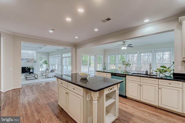 kitchen with dark countertops, open floor plan, a sink, and stainless steel dishwasher