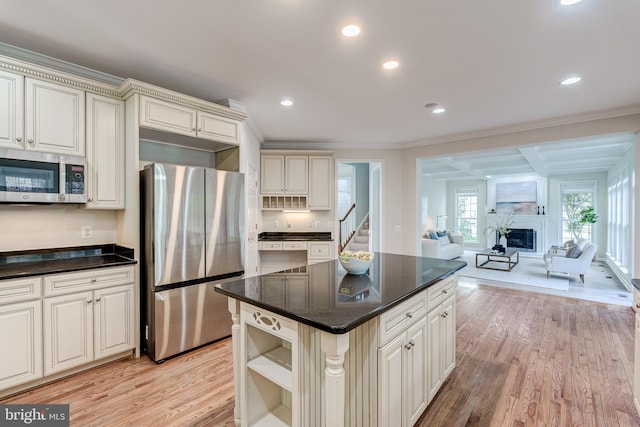 kitchen with ornamental molding, open floor plan, stainless steel appliances, light wood-style floors, and a fireplace