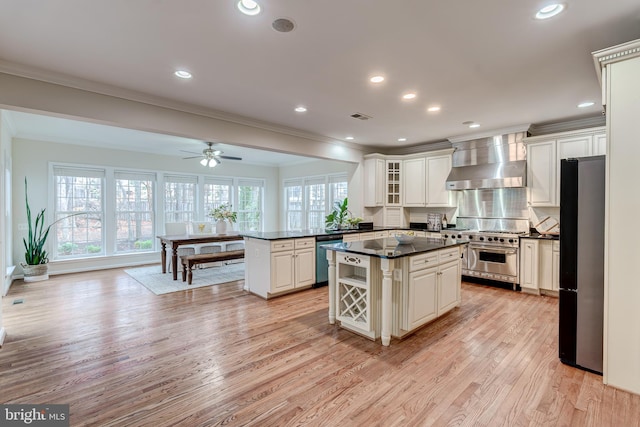 kitchen with stainless steel appliances, visible vents, wall chimney range hood, a center island, and dark countertops