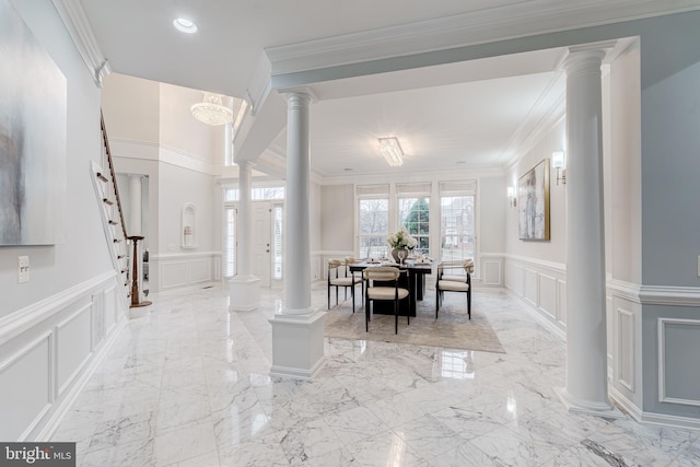 dining space with marble finish floor, decorative columns, ornamental molding, and a decorative wall