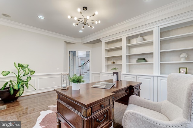 office featuring built in features, a wainscoted wall, ornamental molding, light wood-style floors, and a notable chandelier