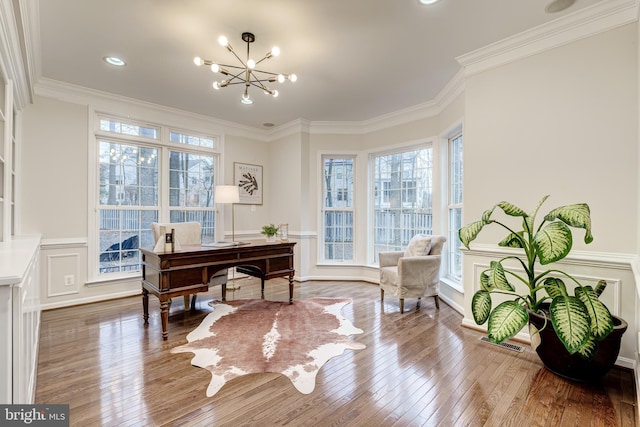 office area with a chandelier, hardwood / wood-style flooring, a decorative wall, visible vents, and crown molding