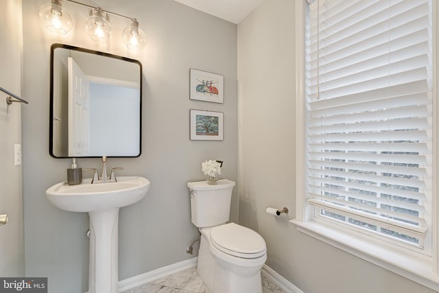 bathroom featuring toilet, marble finish floor, and baseboards