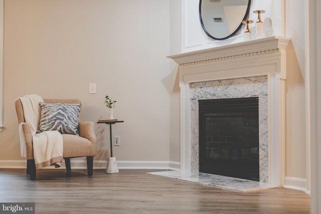 living area with wood finished floors, a high end fireplace, and baseboards