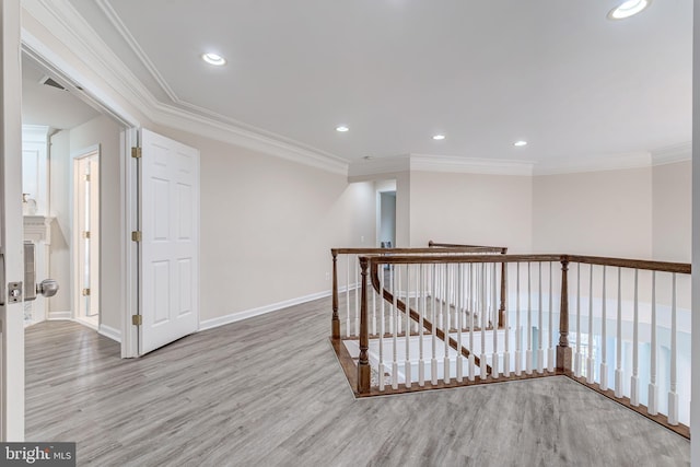 hallway with baseboards, ornamental molding, wood finished floors, and an upstairs landing