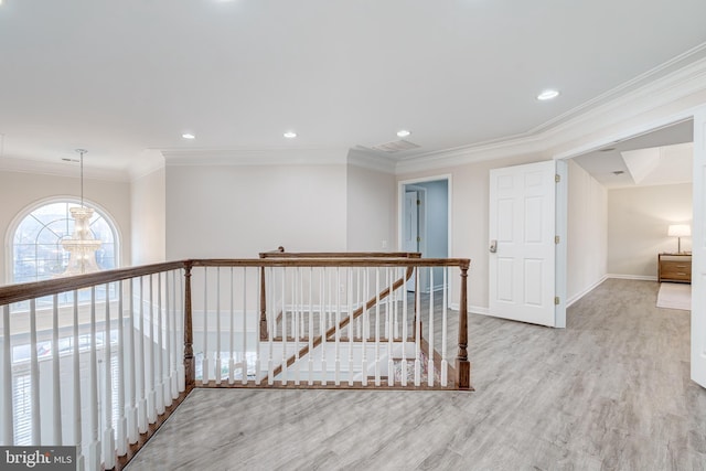 hall with an inviting chandelier, ornamental molding, an upstairs landing, wood finished floors, and baseboards