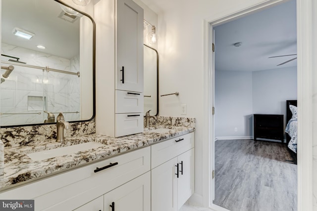 ensuite bathroom featuring double vanity, a marble finish shower, a sink, and wood finished floors