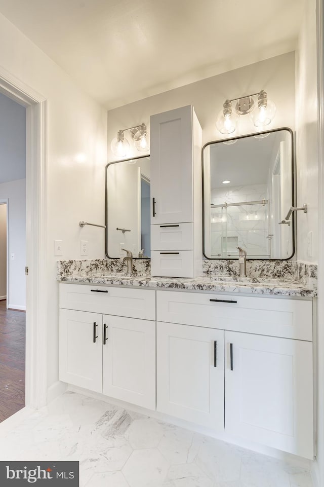 bathroom with double vanity, a stall shower, marble finish floor, and a sink