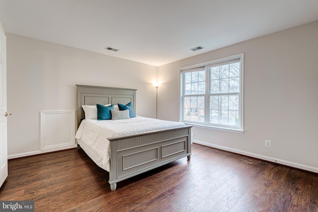 bedroom with visible vents, dark wood finished floors, and baseboards