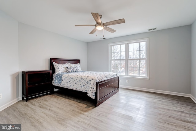 bedroom with light wood finished floors, a ceiling fan, visible vents, and baseboards