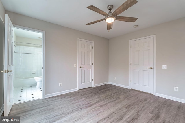 unfurnished bedroom with ceiling fan, connected bathroom, baseboards, and wood finished floors