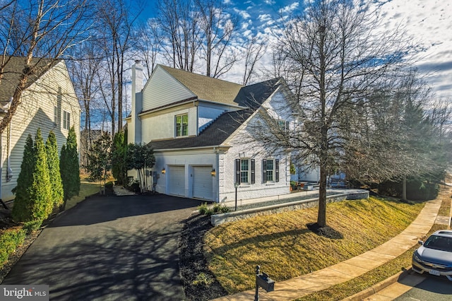 view of front of property featuring an attached garage, brick siding, driveway, stucco siding, and a chimney