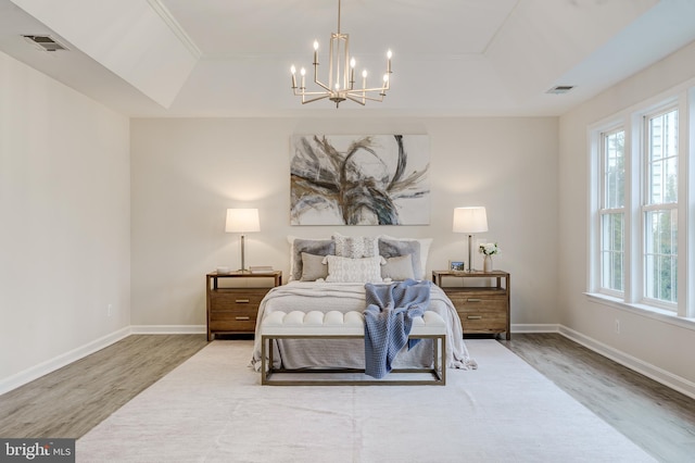 bedroom featuring wood finished floors, a raised ceiling, and visible vents