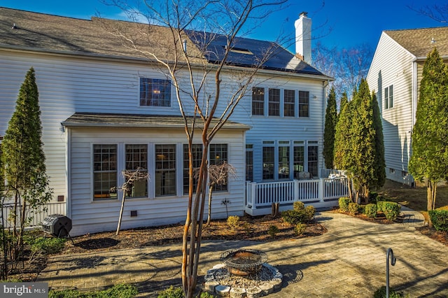 back of property featuring crawl space, an outdoor fire pit, a chimney, and fence