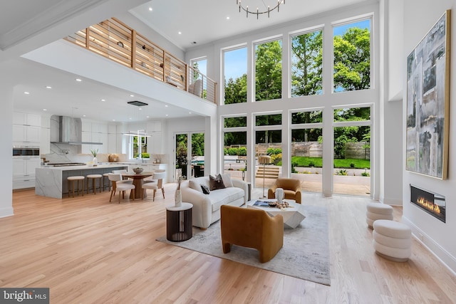 5914 Woodley Rd, Mclean, VA 22101 - living area featuring light wood-style floors, a glass covered fireplace, a high ceiling, recessed lighting, and baseboards