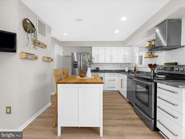 kitchen featuring decorative backsplash, a center island, stainless steel appliances, wall chimney range hood, and white cabinetry