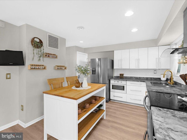 kitchen featuring visible vents, appliances with stainless steel finishes, light wood-style floors, white cabinetry, and a sink