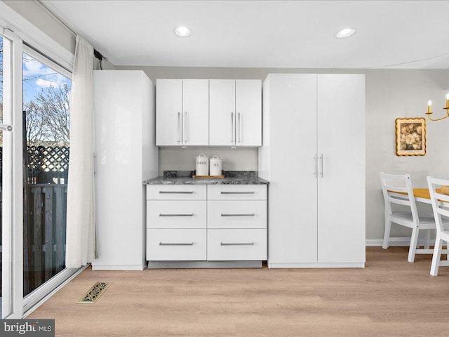 kitchen featuring recessed lighting, visible vents, white cabinets, light wood-type flooring, and dark stone counters