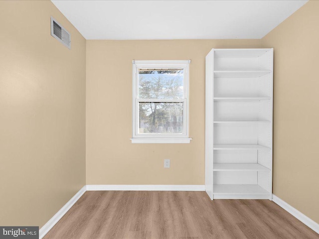 unfurnished room featuring light wood-style floors, visible vents, and baseboards