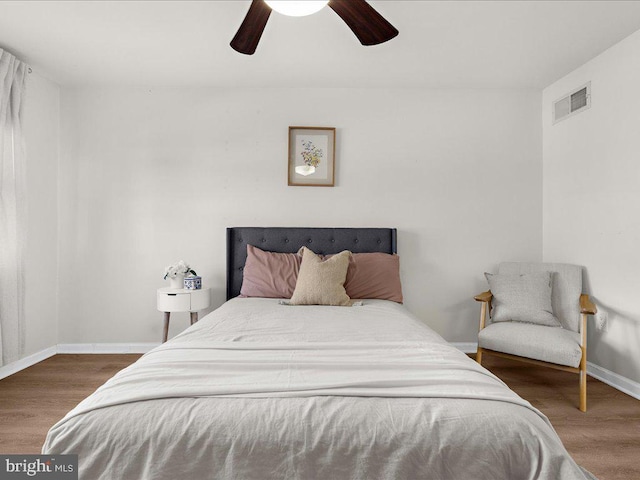 bedroom with a ceiling fan, baseboards, visible vents, and wood finished floors