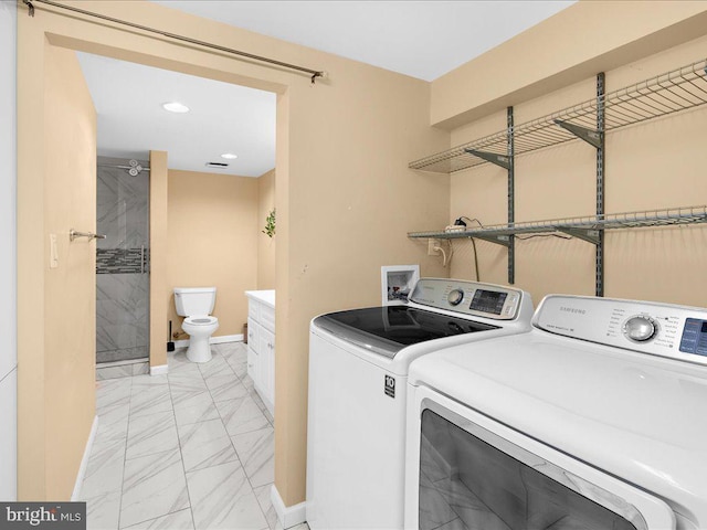 laundry area featuring baseboards, marble finish floor, and washer and dryer