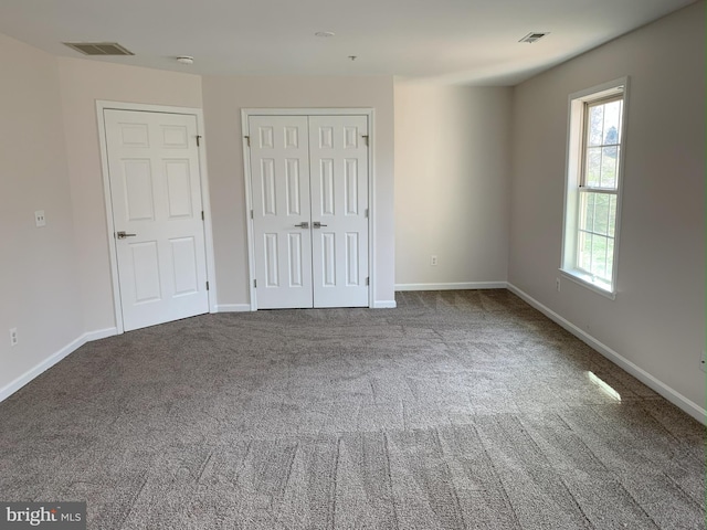 unfurnished bedroom featuring carpet floors, a closet, visible vents, and baseboards