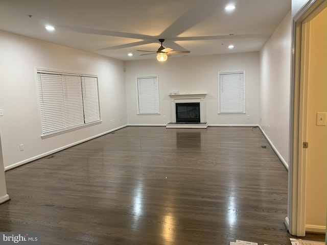 unfurnished living room featuring recessed lighting, dark wood-type flooring, a glass covered fireplace, a ceiling fan, and baseboards