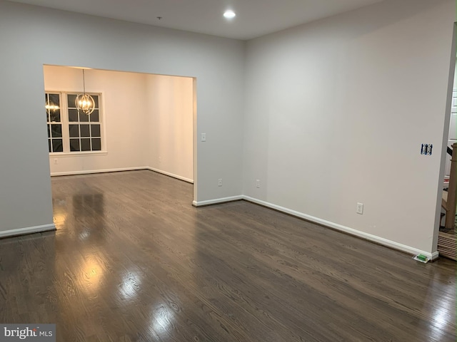 unfurnished room with an inviting chandelier, baseboards, dark wood-style floors, and recessed lighting