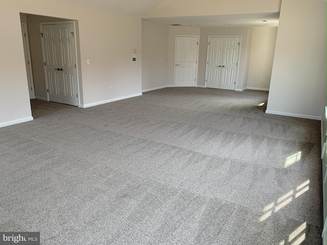 unfurnished room with vaulted ceiling, carpet floors, and baseboards