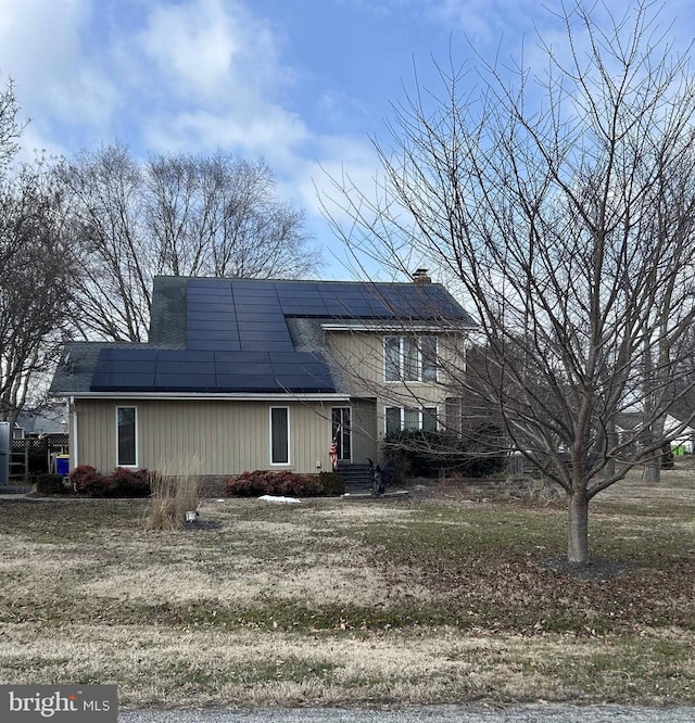 view of front of property with a chimney and solar panels