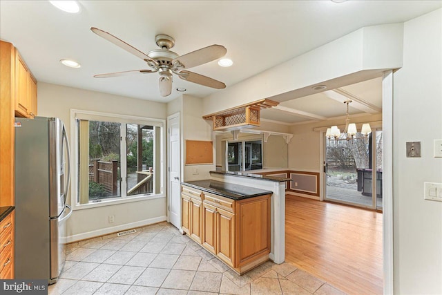 kitchen with dark countertops, a healthy amount of sunlight, stainless steel refrigerator with ice dispenser, and light tile patterned flooring