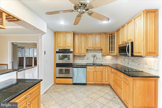 kitchen featuring a sink, appliances with stainless steel finishes, decorative backsplash, dark stone countertops, and glass insert cabinets