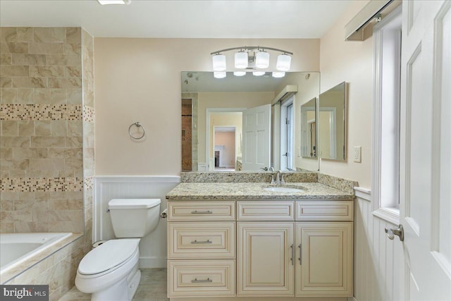 bathroom with a wainscoted wall, vanity, and toilet