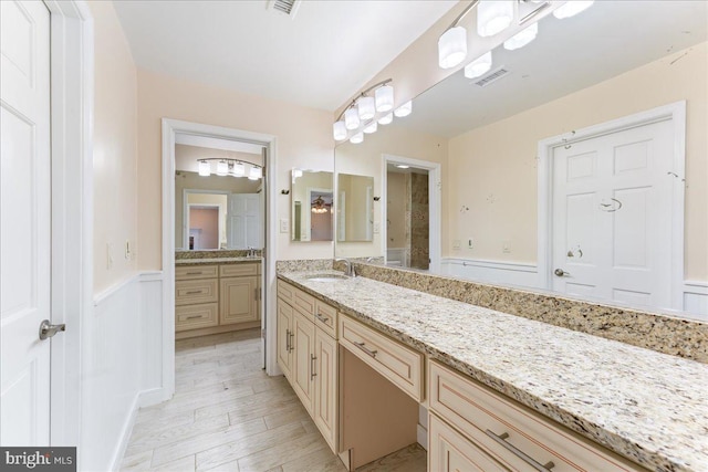 bathroom featuring a wainscoted wall, visible vents, vanity, and wood finished floors