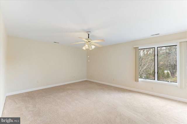 spare room with baseboards, visible vents, ceiling fan, and light colored carpet