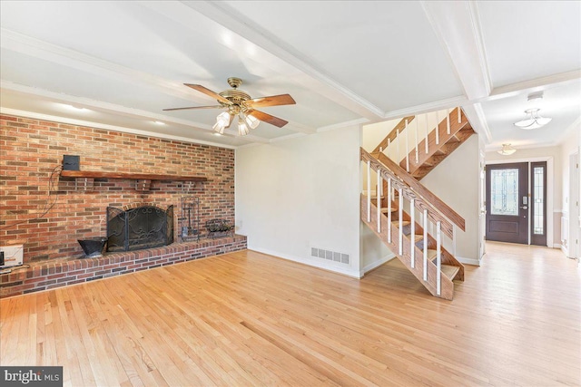 unfurnished living room featuring visible vents, wood-type flooring, stairs, crown molding, and a fireplace