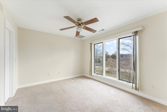 unfurnished room featuring a ceiling fan, visible vents, light carpet, and baseboards