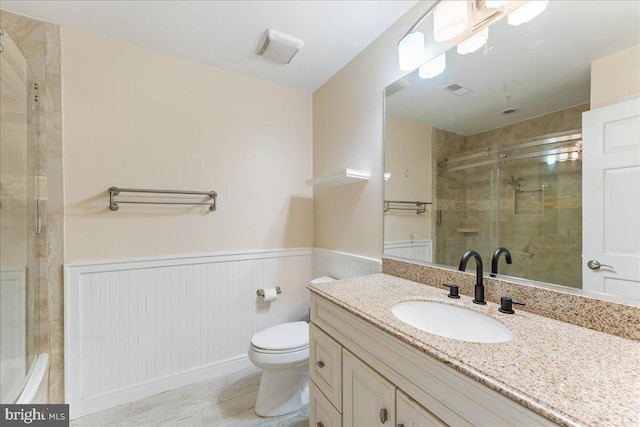 full bath with vanity, wainscoting, a shower stall, and toilet