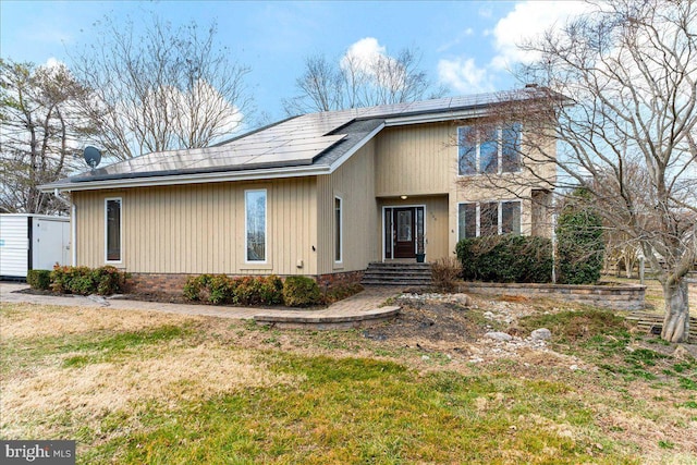 view of front of home featuring a front lawn and roof mounted solar panels