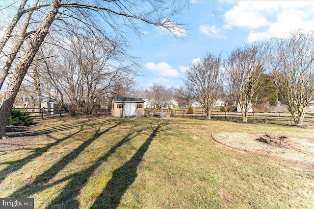 view of yard with an outbuilding, a shed, an outdoor fire pit, and fence