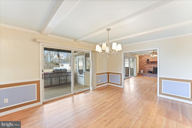 unfurnished dining area featuring a notable chandelier, a fireplace, wood finished floors, ornamental molding, and beam ceiling