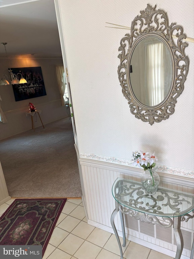 corridor featuring light tile patterned floors, a wainscoted wall, and wallpapered walls