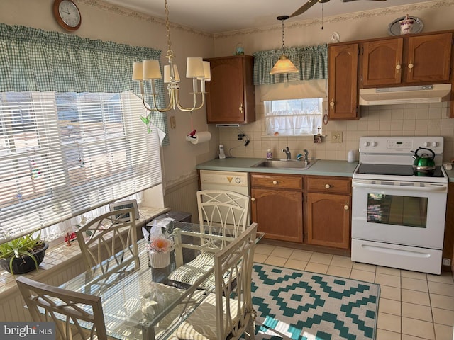 kitchen with white appliances, decorative light fixtures, light countertops, under cabinet range hood, and a sink