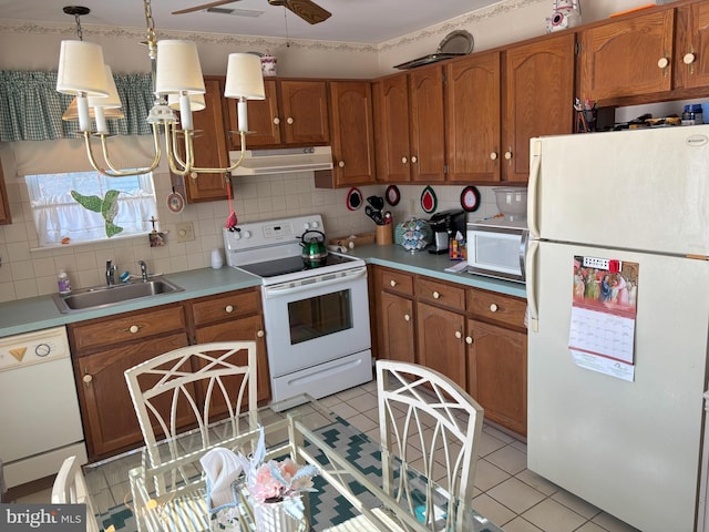 kitchen featuring hanging light fixtures, white appliances, brown cabinetry, and a sink